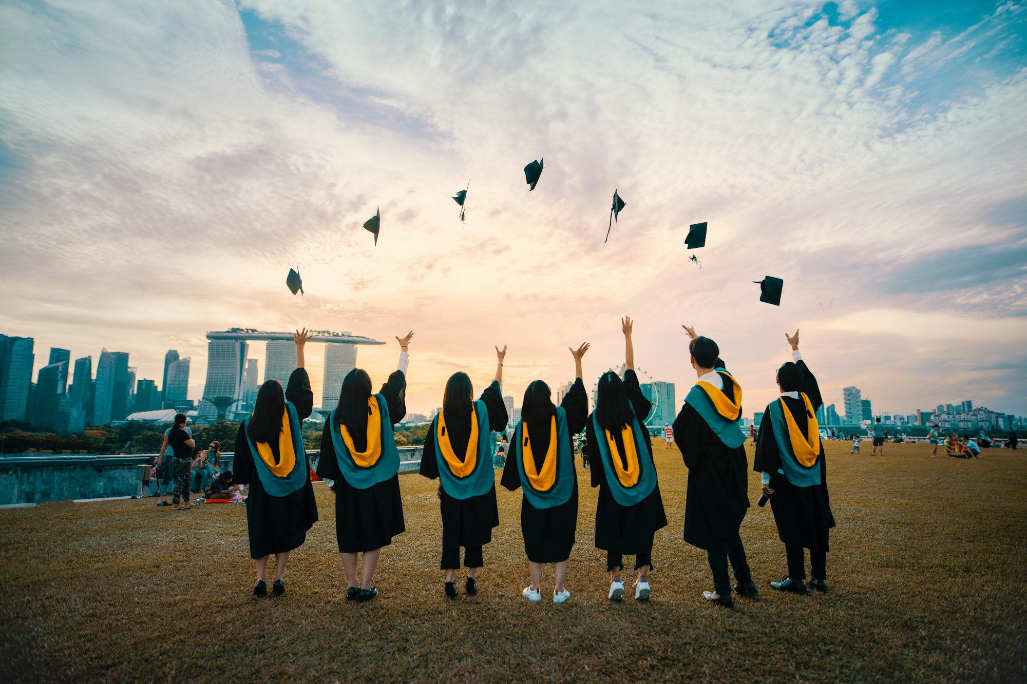 Graduates tossing their caps toward the sky with a city skyline behind them